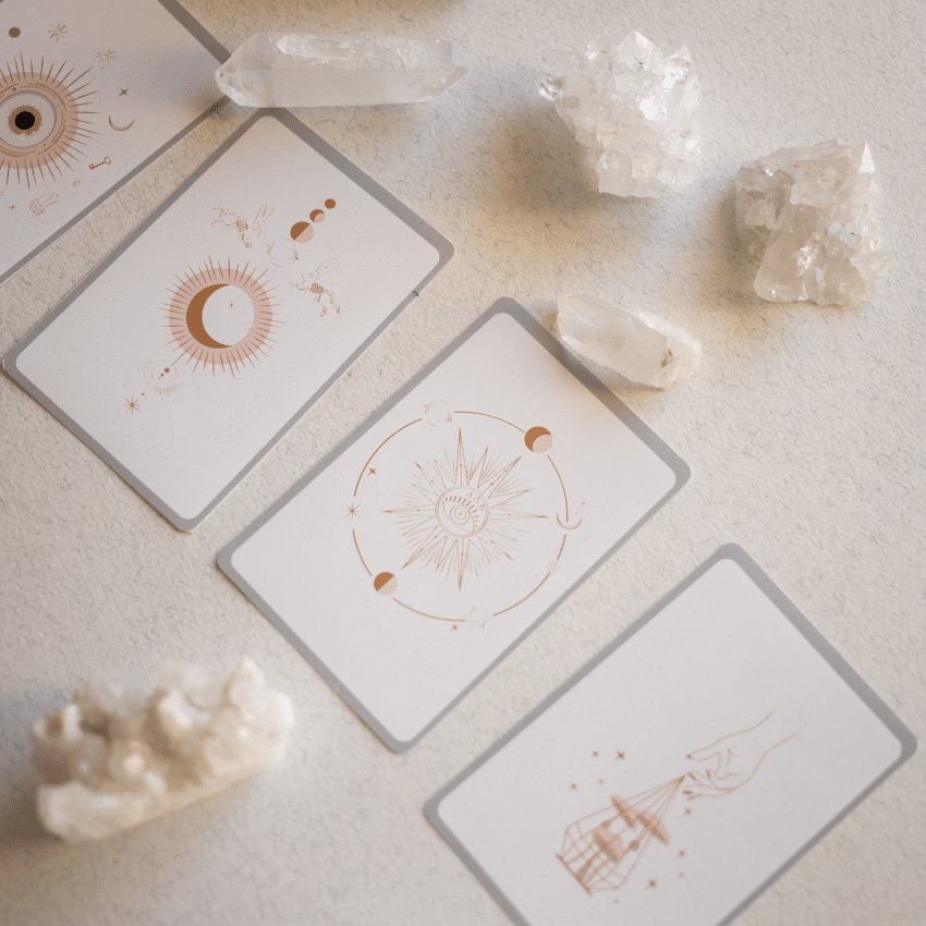 Four white Tarot cards on a white background surrounded by crystals.