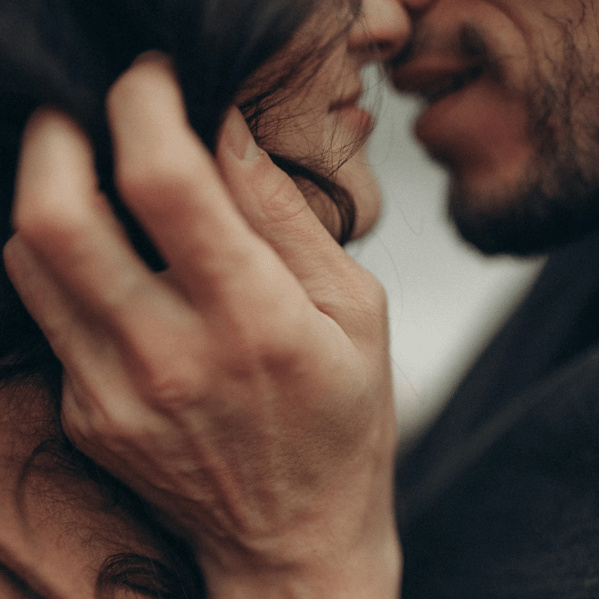A couple are about to kiss. A bearded man holds a woman