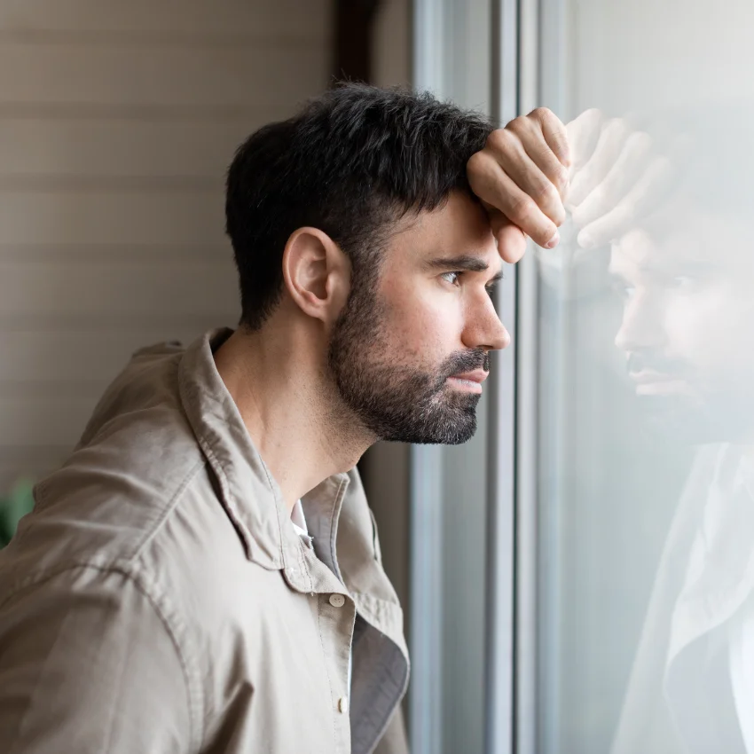 homme réfléchi en regardant par la fenêtre